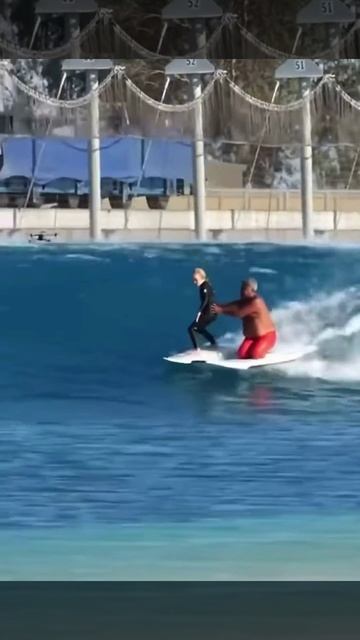 Инструктор по сёрфингу обучает ученика, стоя на коленях на собственной доске